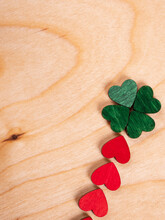 A Four-leaf Clover Made Of Green Hearts With A Red Stem Is Laid Out On A Wooden Background