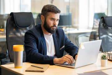 Leinwandbilder - Young serious businessman preparing report for conference or seminar in office