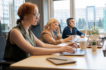 Leinwandbilder - Mature businesswoman and her young busy colleagues working individually