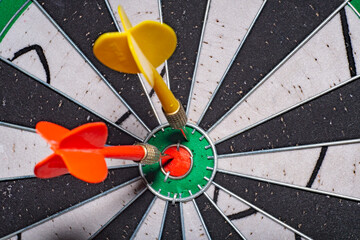 Blurred background in soft focus with a darts board with a closeup of an arrow hitting the center and an opponent's arrow stuck nearby. Concept - fierce competition in business