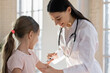 © fizkes - Smiling female pediatrician wearing uniform with stethoscope vaccinating little girl in hospital, doctor gp making prick, injection to preschool girl in clinic, children healthcare concept