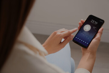 Wall Mural - woman using weather forecast app on smartphone indoors, closeup