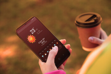 Wall Mural - woman using weather forecast app on smartphone outdoors, closeup