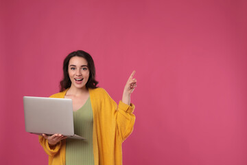 Wall Mural - Young woman with laptop on pink background. Space for text