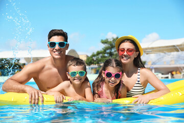 Poster - Happy family with inflatable mattress in swimming pool. Summer vacation