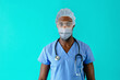 © Carlos David - Portrait of a young african male er doctor wearing mask  and glasses for covid-19 corona virus protection against blue studio background