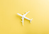 Fototapeta Boho - World Tourism Day, Top view flat lay of minimal toy model plane, airplane with copy space, studio shot isolated on a yellow background, accessory flight holiday concept