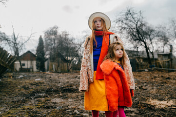 Two cute little sisters in old clothes spend a lot of time together in the village on the autumn holidays