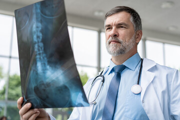 Wall Mural - Mature Doctor looking at an x-ray results in a hospital.