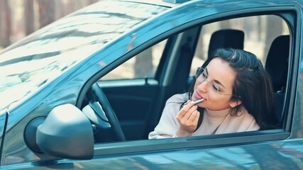 Wall Mural - Young woman sit in car during travelling break. Slow motion of girl applying lipstick on lips. Cosmetics time and face care. Make up routine.