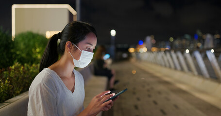 Canvas Print - Woman wear face mask and use of mobile phone at street in evening