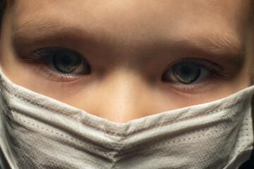 Portrait of a child in a protective mask on his face with a sad look, Covid-19 coronavirus pandemic, virus protection