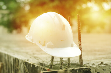 Closeup white safety helmet hanging on the rusted reinforcement steel at the abandoned construction site. Unemployment concept