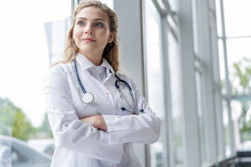 Wall Mural - Portrait of young woman doctor with white coat standing in hospital.