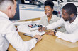 © alfa27 - black clients sign a contract while sitting at table with salesman, professional worker of dealership explain terms of the contract and show where to sign