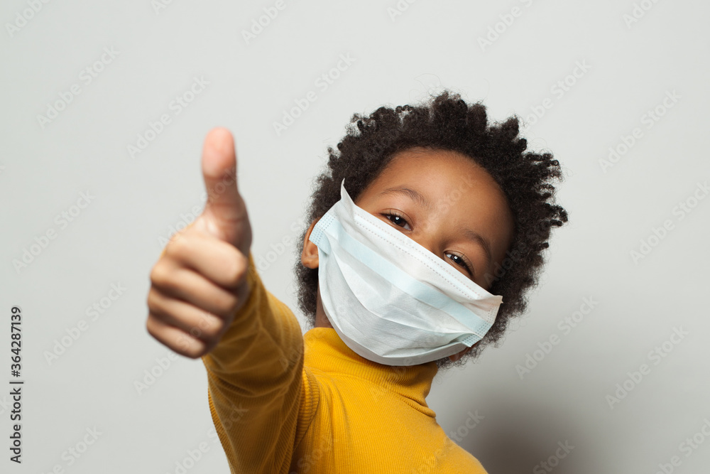 Happy African American black kid in medical protective face mask showing thumb up on white - obrazy, fototapety, plakaty 