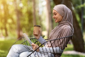 Wall Mural - Smiling arab girl holding digital tablet and coffee to go