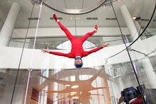 Levitation Of Sports People In A Wind Tunnel. Jumping Without A Parachute In A Wind Tunnel Indoors. Man In A Red Suit, Portrait Of A Skydiver,  Flies Head Down. Extreme Sport