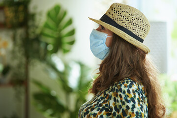 Side view of stylish middle aged woman in straw hat with mask