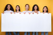 © Prostock-studio - Women Holding Blank Paper Board Advertising Something Over Yellow Background