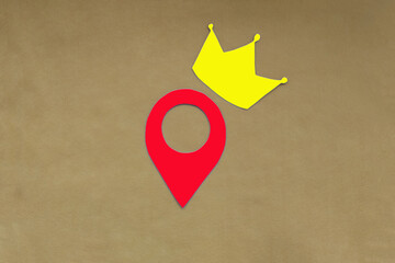 Fototapete - The crown is yellow, and the geolocation sign is red on a light brown background. Determining the main location.