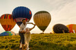 © Angelov - Beautiful romantic couple hugging at meadow. hot air balloon on a background