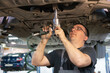 © Дмитрий Ногаев - Car repair. Car mechanic unscrews the car nuts with a pneumatic wrench