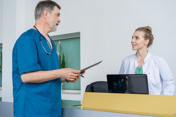 Wall Mural - Doctor In Discussion With Nurse At Nurses Station or Hospital Reception.