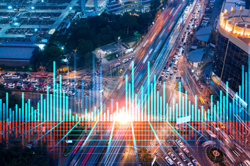 FOREX and stock market chart hologram on aerial view of road, busy urban traffic highway at night. Junction network of transportation infrastructure. The concept of international trading.