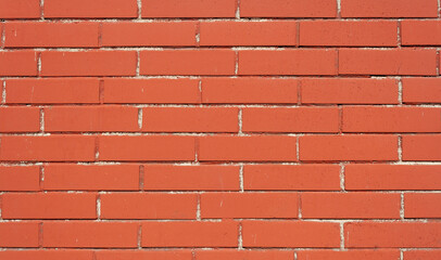 Red brick texture. Brown brick wall with uneven seam. Building pattern. The construction of a stone wall. Old concrete fence with a shadow from the sun. Close-up design.