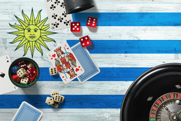 Wall Mural - Uruguay casino theme. Aces in poker game, cards and chips on red table with national wooden flag background. Gambling and betting.