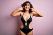 © Krakenimages.com - Young beautiful arab woman on vacation wearing swimsuit and sunglasses over pink background smiling cheerful showing and pointing with fingers teeth and mouth. Dental health concept.