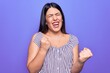 © Krakenimages.com - Young beautiful brunette woman wearing casual striped t-shirt standing over purple background celebrating surprised and amazed for success with arms raised and eyes closed