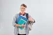 © DragonImages - Portrait of happy handsome young high school student with textbooks showing thumbs-up and smiling at camera