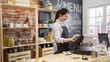 © PRPicturesProduction - smiling coffee shop assistant using pos point of sale terminal to put in order from note paper at restaurant register. waitress lady working in counter in cafe store. young girl staff using cashbox.