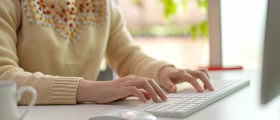 Female employee typing on computer keyboard on white office desk in office room