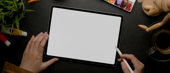 Poster - female designer drawing on mock up tablet with stylus pen on worktable with painting tools