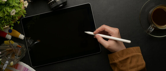 Poster - female designer drawing on digital tablet with stylus pen on worktable with painting tools