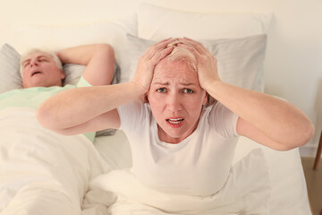 Canvas Print - Mature irritated woman in bed with snoring husband