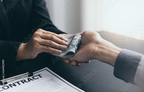 Fotografía Young man's hand received a dollar from the woman's hand in the office to bribe