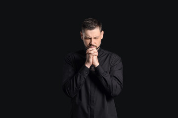 Wall Mural - Handsome praying priest on dark background