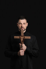 Wall Mural - Handsome priest with cross on dark background