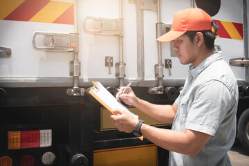 Asian a truck driver holding clipboard his checking safety container truck steel door.