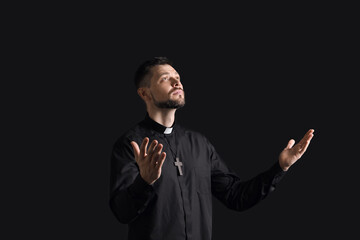 Wall Mural - Handsome praying priest on dark background