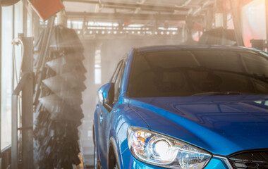 Wall Mural - Blue SUV car washing by automatic car washing machine. Auto care. Car cleaning with high pressure water spray after clean by auto brush. Car cleaning before waxing service. Carwash service business.