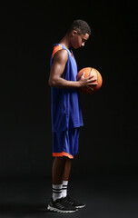 Wall Mural - Young African-American basketball player on dark background