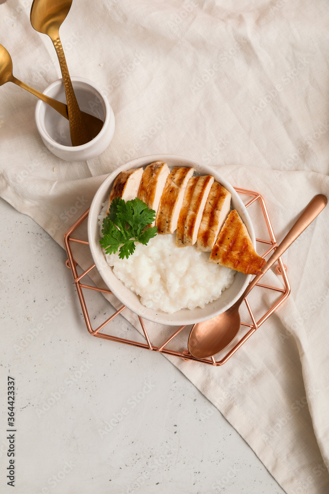 Bowl with boiled rice and chicken on table