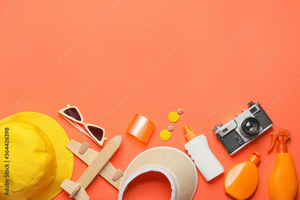 Travel accessories with sunscreen cream on color background