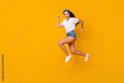 Full size profile side photo cheerful enthusiastic girl jump run after spring free time novelty adverts scream wear white t-shirt shoes blue headband isolated shine bright color background