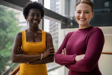 Diverse young businesswomen smiling while standing together in an office